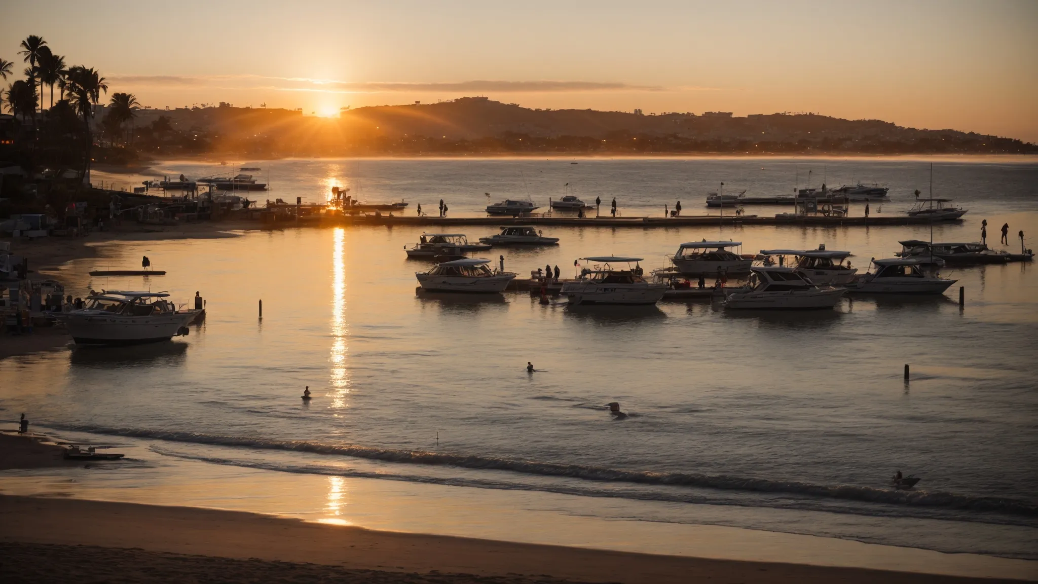 sunset over the sparkling water of mission bay, with rvs parked close to the shore and families enjoying a bonfire on the beach.