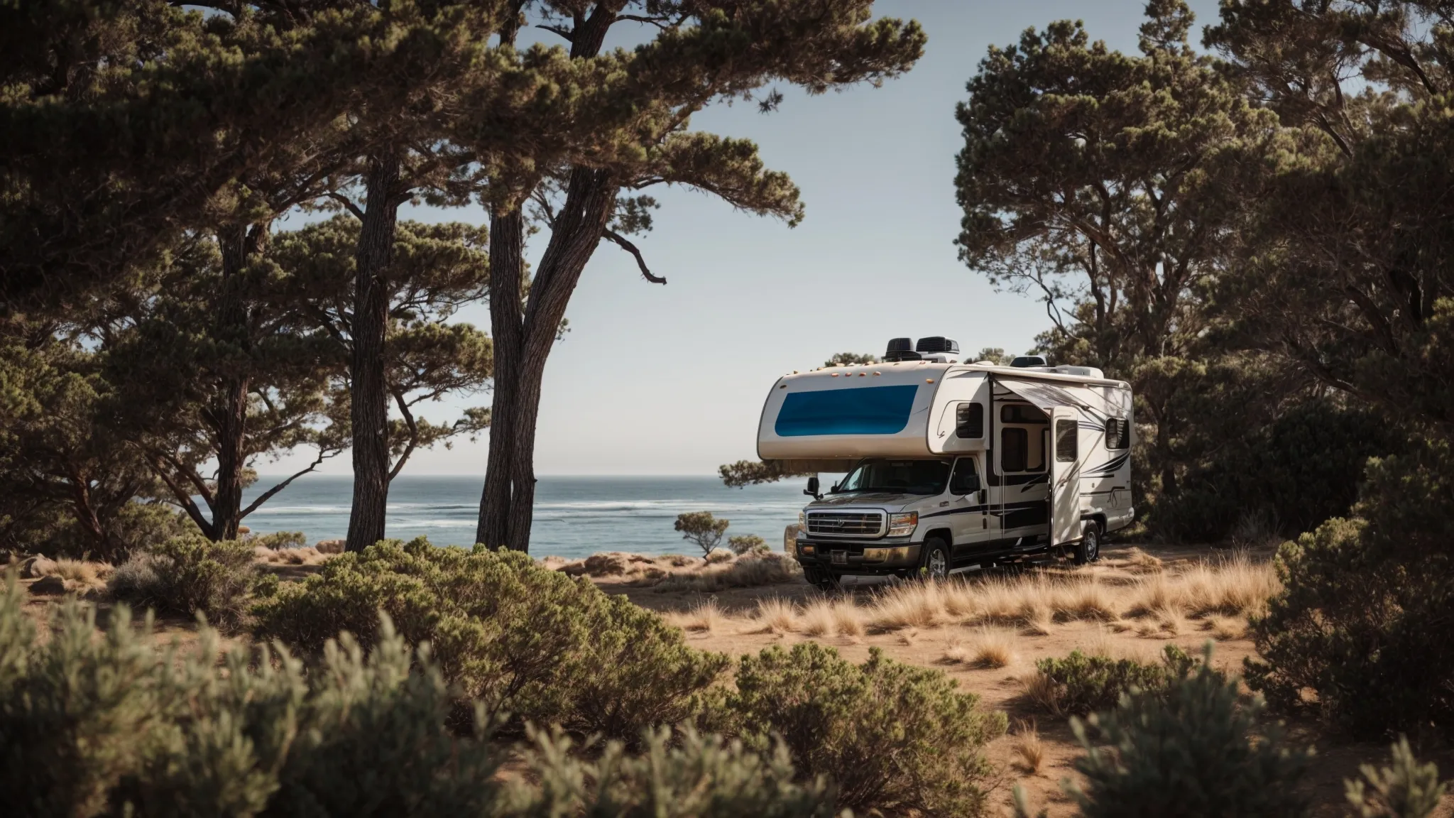 an rv settled among trees at a tranquil san diego campground with the pacific ocean in the background.