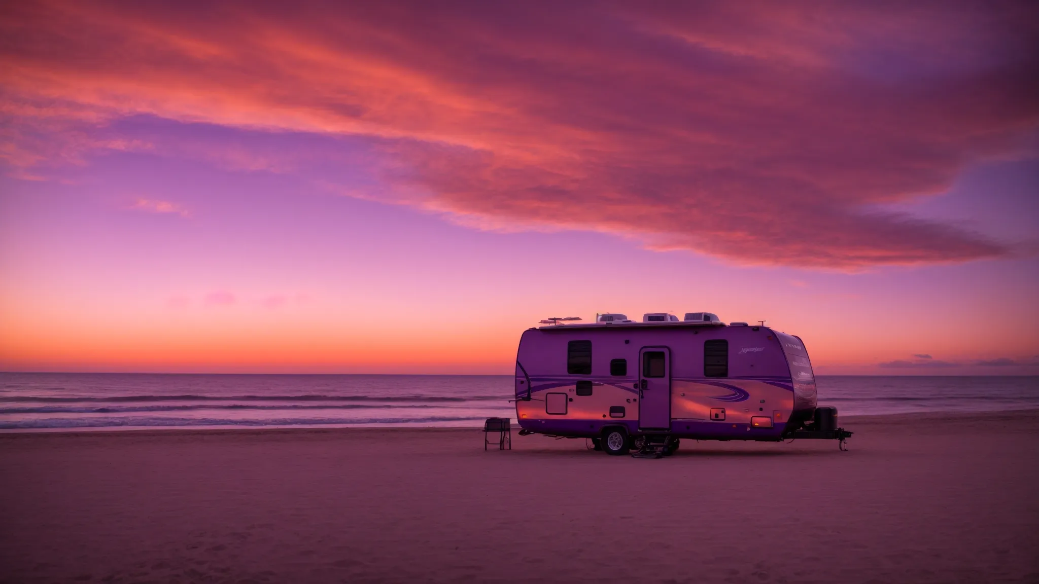 an rv parked by the serene beach with the sunset painting the sky in hues of orange and purple.